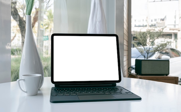 Tablet de tela em branco de maquete com teclado na mesa branca.