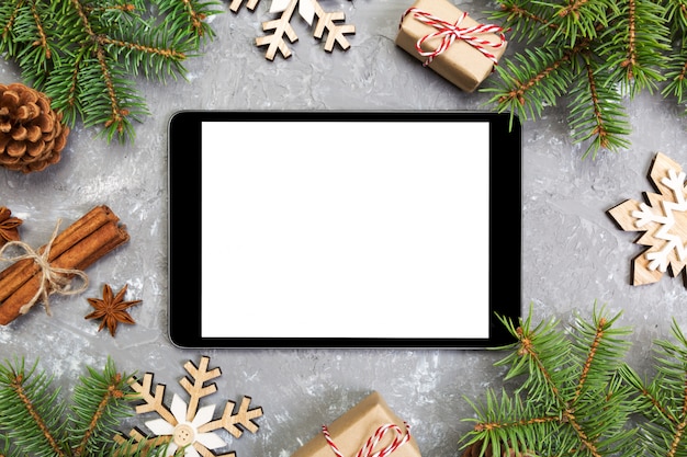 Tablet digital com decorações de fundo de cimento cinza rústico de Natal para apresentação do aplicativo. vista superior com copyspace