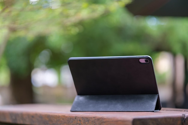 Tablet digital com teclado sem fio em mesa de madeira ao ar livre