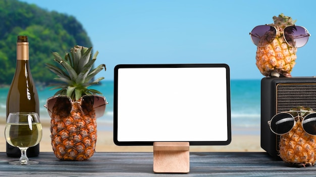 Tablet digital e bebidas de verão na mesa de madeira com praia tropical no fundo Conceito de férias de verão