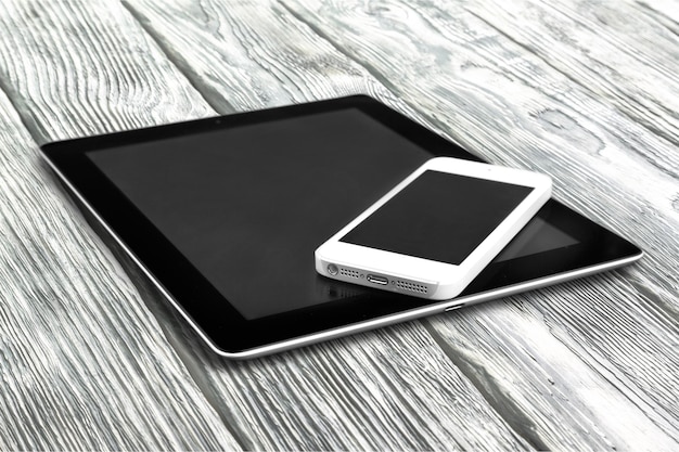 Tablet digital e telefone em fundo de madeira