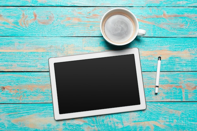 Tablet digital e xícara de café na mesa de madeira