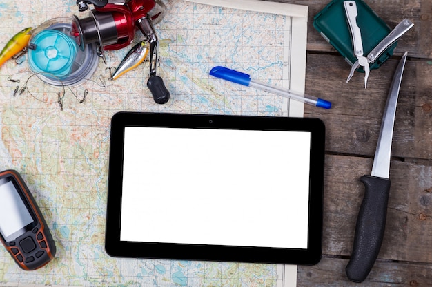 Tablet digital em branco com equipamentos de pesca e navegador no mapa