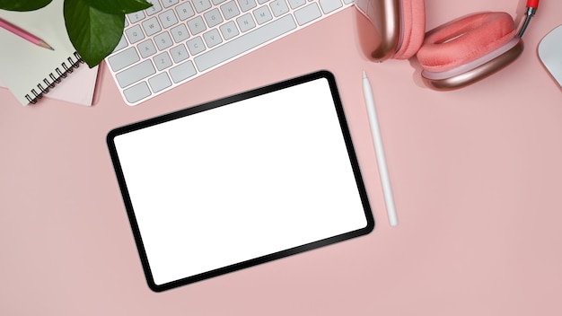 Tablet digital plano leigo com tela branca caneta stylus fone de ouvido xícara de café e notebook em fundo rosa