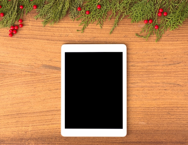 Tablet-Display auf dem Tisch mit isolierten weißen Bildschirm für Mockup in der Weihnachtszeit