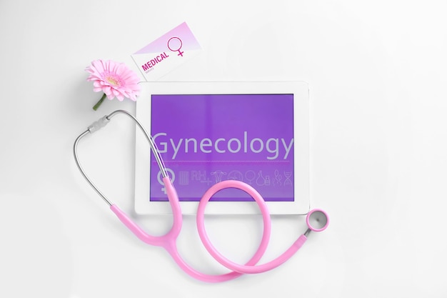 Tablet e estetoscópio no conceito de ginecologia de vista superior de fundo branco