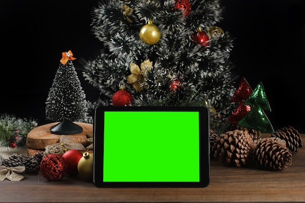 Tablet em fundo preto com decoração de Natal e mesa de madeira.