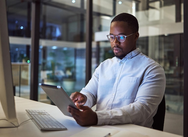 Tablet empresário negro e análise de dados com computador no escritório noturno para código de segurança cibernética de software de marketing digital ou desenvolvedor de programador kpi pensando ou designer de sites com tecnologia