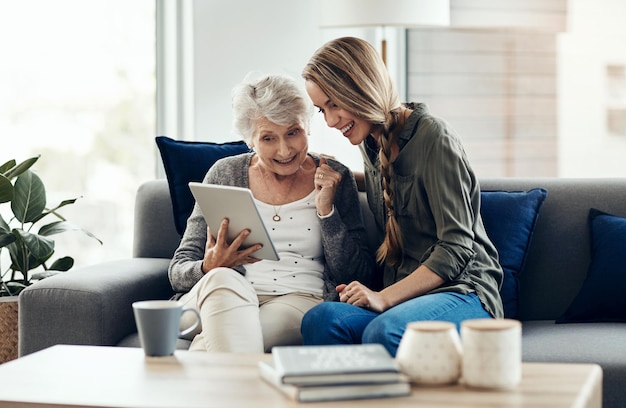 Tablet feliz y mujer con madre mayor en casa para ayuda con blog en línea internet o conectividad vinculación relajarse y anciana mujer aprendiendo tecnología digital con la hija en casa