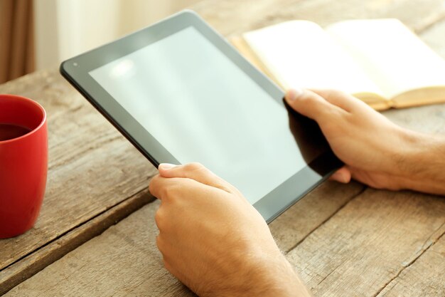 Tablet im Handbuch des Menschen und Tasse Tee auf Holztisch