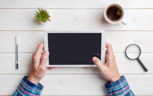 Tablet in der Hand Mockup auf dem Schreibtisch Draufsicht flach Zusammensetzung Nahaufnahme Weißer Holzschreibtisch