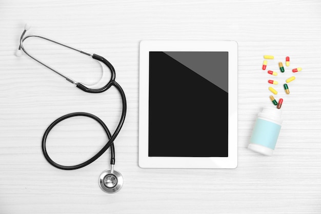 Tablet médico com estetoscópio em fundo de madeira