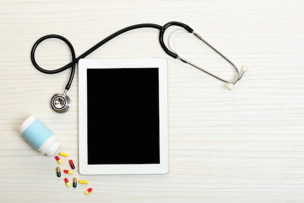 Tablet médico com estetoscópio em fundo de madeira