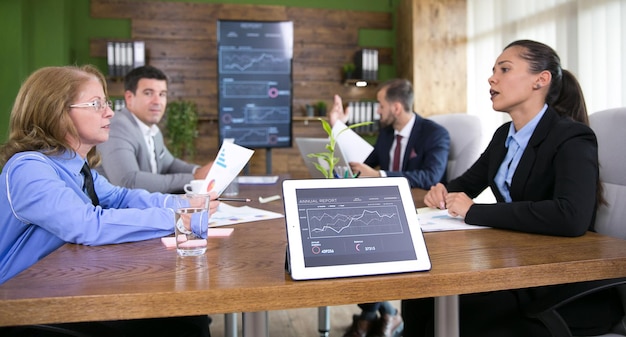 Tablet mit Diagrammen und Geschäftsleuten, die im Konferenzraum arbeiten. Moderne Technik im Konferenzraum.