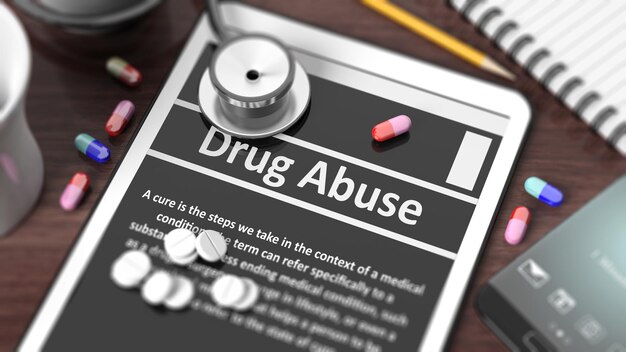 Tablet mit Drogenmissbrauch auf dem Bildschirm, Stethoskoppillen und Gegenstände auf dem Holzdesktop