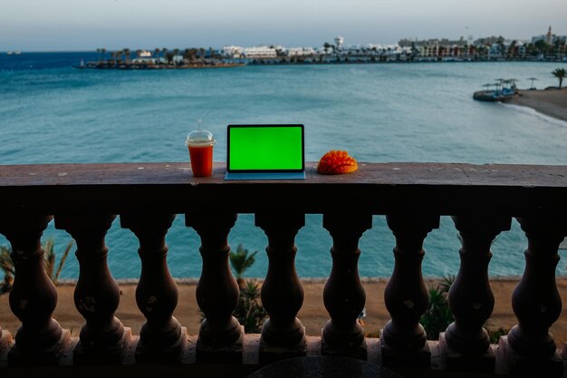 Tablet mit grünem Bildschirm auf Balkon mit Meerblick