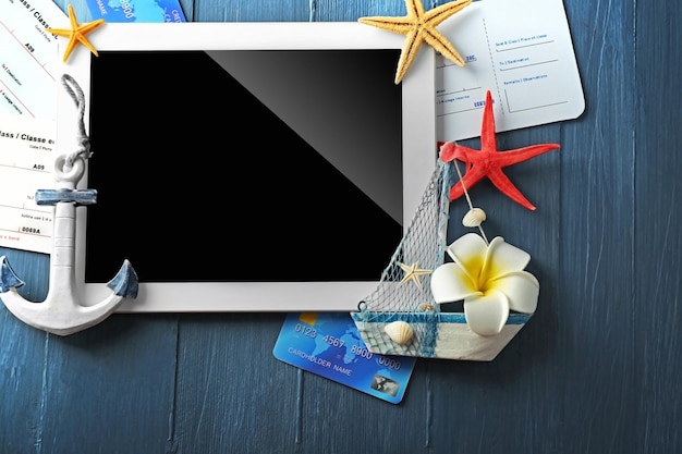 Foto tablet mit kreditkarten und flugtickets für den urlaub auf blauem holztisch
