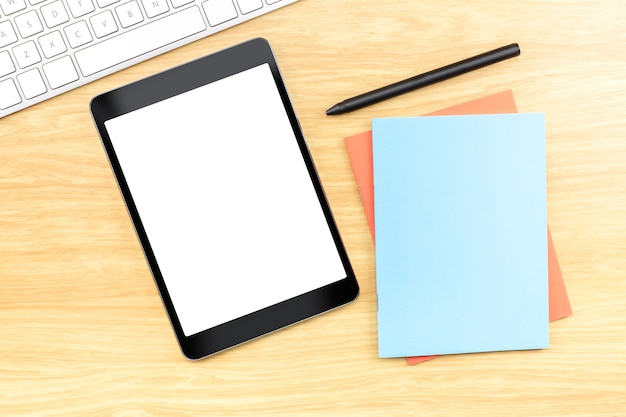 Tablet móvel de tela em branco com caderno azul e caneta na mesa de madeira