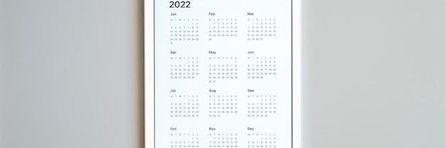 Foto tablet pc con una aplicación abierta de calendario para el año 2022 sobre un fondo gris. concepto de negocio o para hacer una lista de objetivos con el uso de tecnología. vista superior, endecha plana. bandera