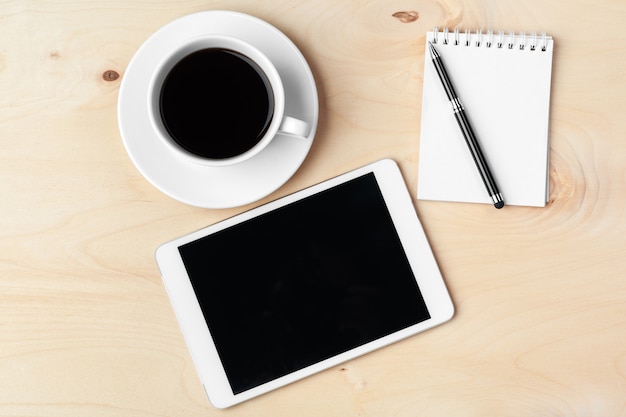 Tablet pc e xícara de café digitais na mesa de madeira.