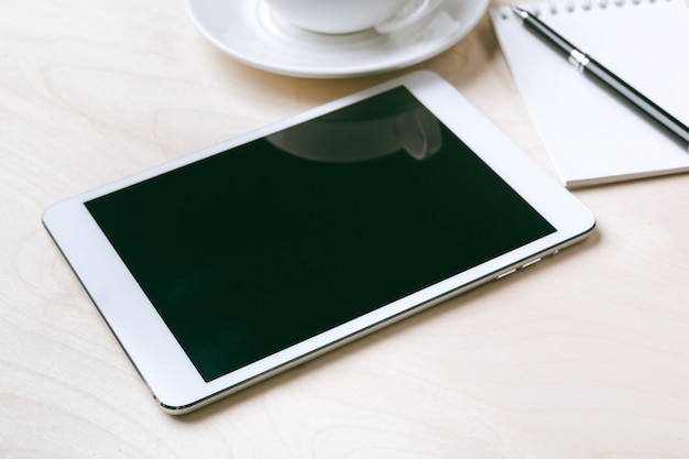 Tablet pc e xícara de café digitais na mesa de madeira.