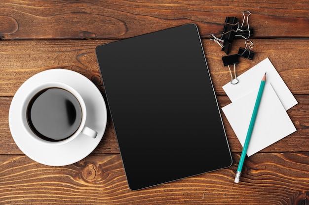 Tablet pc e xícara de café digitais na mesa de madeira.