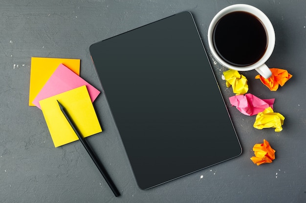 Tablet pc e xícara de café digitais na mesa de madeira.