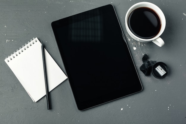 Tablet pc e xícara de café digitais na mesa de madeira.