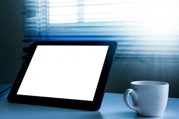 Tablet PC con pantalla en blanco y una taza de café sobre la mesa