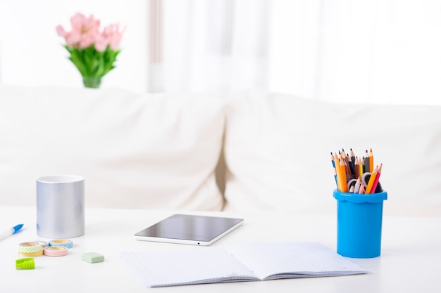 Tablet PC con pantalla vacía blanca junto a la taza de agua