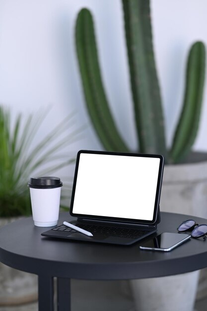 Tablet PC portátil y taza de café en la mesa negra en la cafetería.