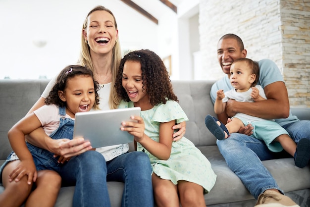 Tablet rindo e família assistindo a um vídeo ou comédia engraçada ou filme de quadrinhos juntos na sala de estar. União feliz e crianças transmitindo um programa em tecnologia digital com seus pais em casa