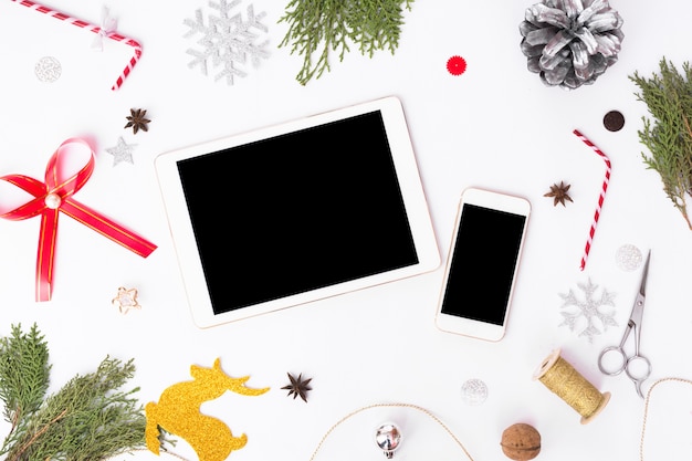 Tablet-Smartphone-Display auf dem Tisch mit isolierten weißen Bildschirm für Mock-up in der Weihnachtszeit