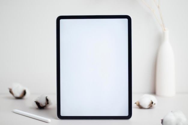 Tablet tela branca vazia com lápis e flor de algodão na maquete de fundo branco para design