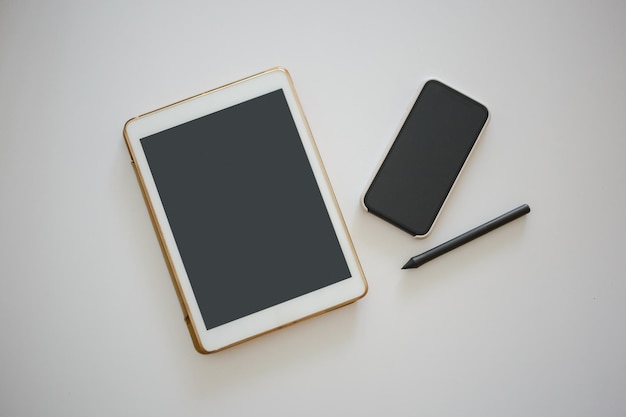 Tablet, telefone e caneta estão no escritório em uma mesa branca