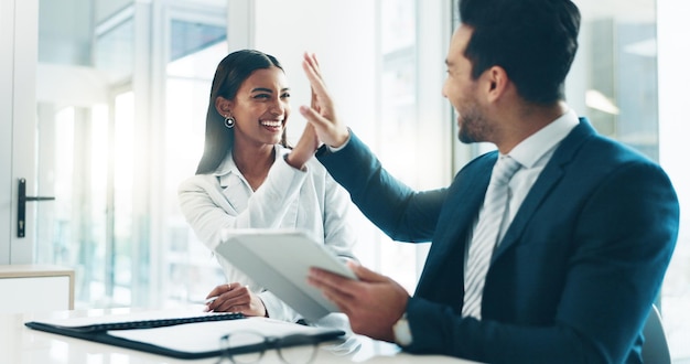 Tableta alta cinco y éxito con gente de negocios en una oficina como equipo ganador para un crecimiento profesional Asociación tecnológica o promoción con un hombre y una mujer empleados en celebración de un bono