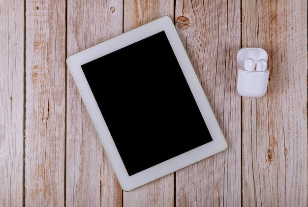 Foto tableta blanca con una pantalla en blanco en los auriculares inalámbricos