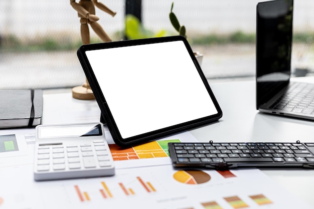 La tableta se coloca sobre la mesa, en la pantalla de la tableta se muestra un fondo blanco en blanco para la ilustración, la pantalla de maqueta para una mayor edición se puede utilizar para una variedad de tareas. copie el espacio.