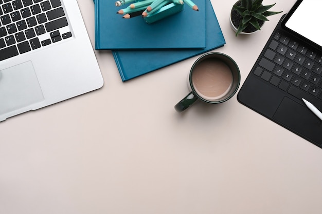 Tableta, cuaderno y taza de café en la mesa blanca