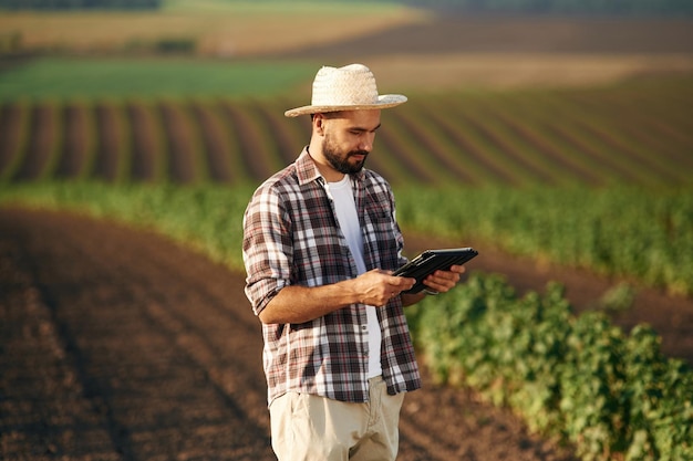 Tableta digital en las manos El granjero está en el campo agrícola