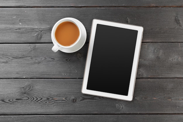 Tableta digital en mesa de madera en café con taza de café