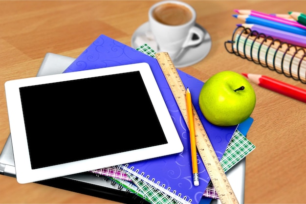 Tableta digital moderna con manzana y cuadernos aislado sobre fondo de madera