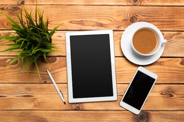 Tableta digital y taza de café en la mesa de madera