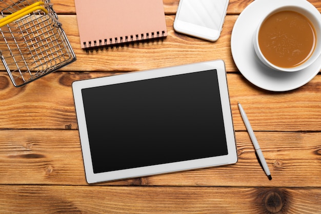 Tableta digital y taza de café en la mesa de madera