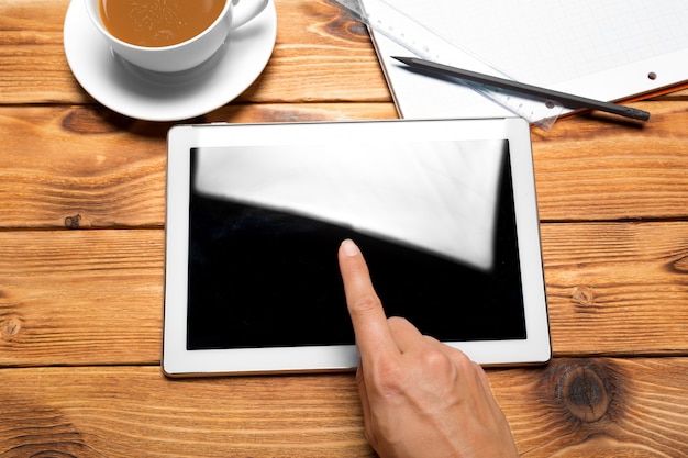 Tableta digital y taza de café en mesa de madera