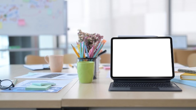 Tableta digital con teclado inalámbrico y suministros en una mesa de madera en una oficina cómoda