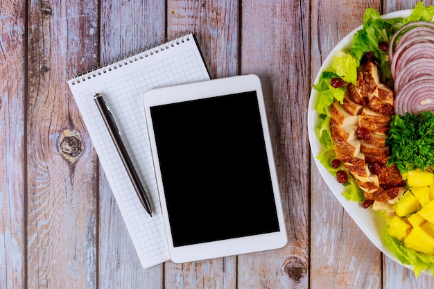 Tableta con ensalada saludable en mesa de madera