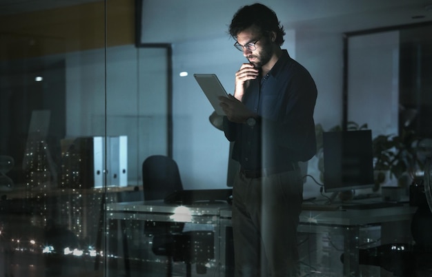 Tableta de hombre de negocios y pensando en resolver problemas de oficina o buscando una solución por ventana con luces de la ciudad por la noche Idea de tecnología y persona profesional con pantalla táctil para enfocarse en leer