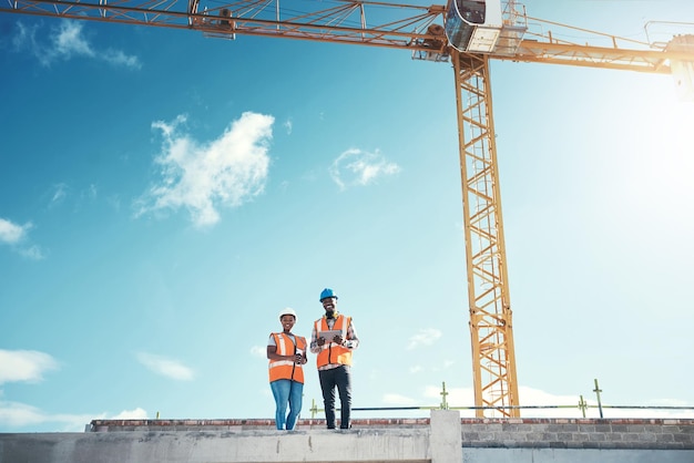 Tableta de ingeniería y equipo en el techo del edificio en el sitio de construcción para el desarrollo de la visión o la arquitectura Mujer y hombre negros al aire libre para proyectos de ingeniería o inspección de seguridad con maqueta del cielo