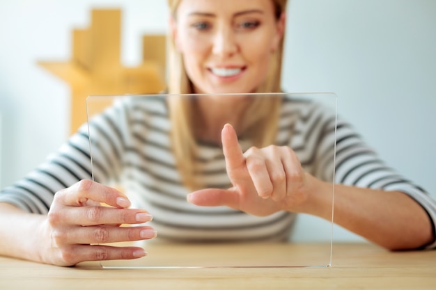 Tableta innovadora. Enfoque selectivo de un dispositivo electrónico moderno en manos de una mujer positiva inteligente alegre